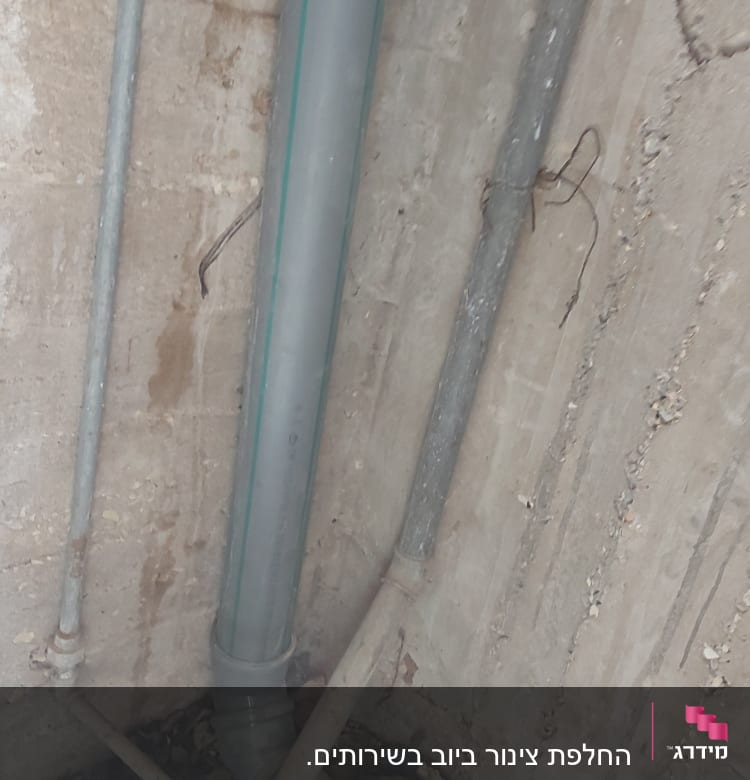 צינורות פלסטיק וברזל על קיר בטון